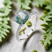 Silver ring with a green gemstone on a white background