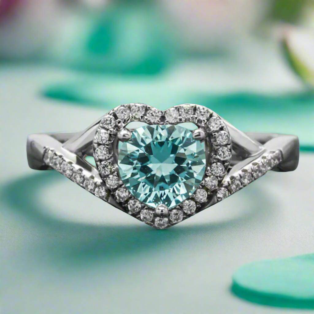 Silver ring with a heart-shaped blue gemstone on a teal background