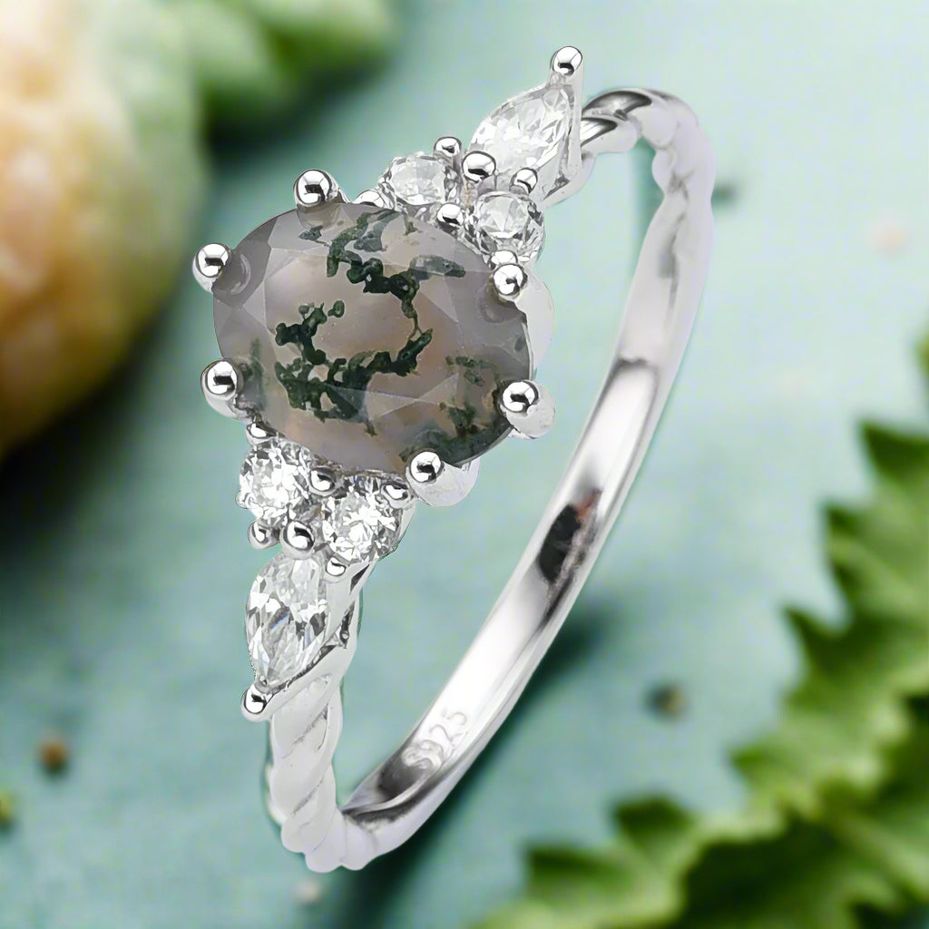 Silver ring with a heart-shaped gemstone and smaller diamonds on a white background
