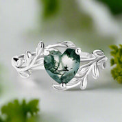 Silver ring with a heart-shaped green gemstone on a white background