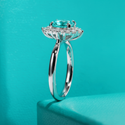 Silver ring with a large blue gemstone on a teal background