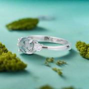 Silver ring with a large green gemstone on a light blue background
