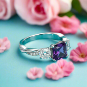 Silver ring with a purple gemstone on a teal background