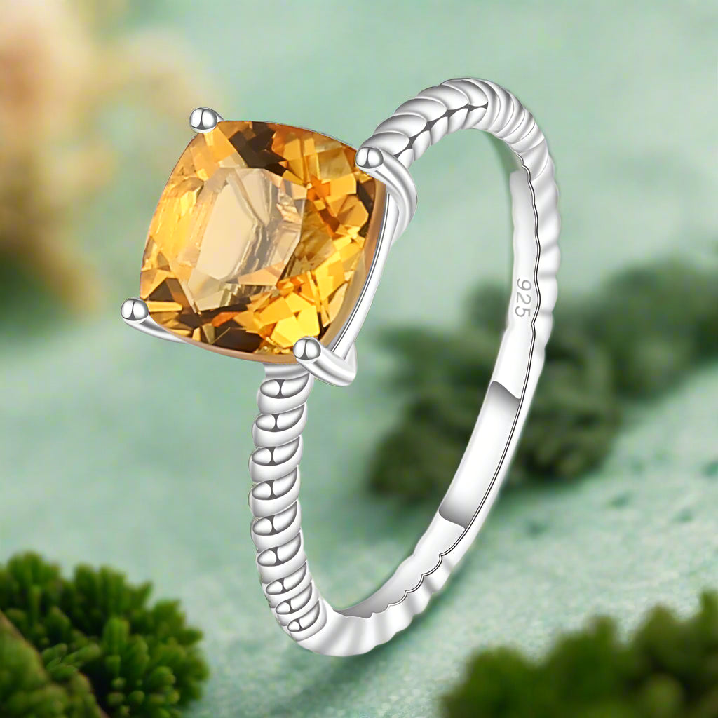 Silver ring with a yellow gemstone on a white background