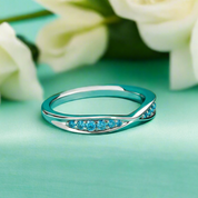 Silver ring with blue gemstones on a green background with white flowers