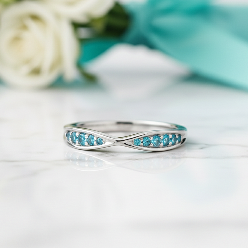 Silver ring with blue gemstones on a green background with white flowers