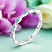 Silver ring with blue gemstones on a light green background with flowers.