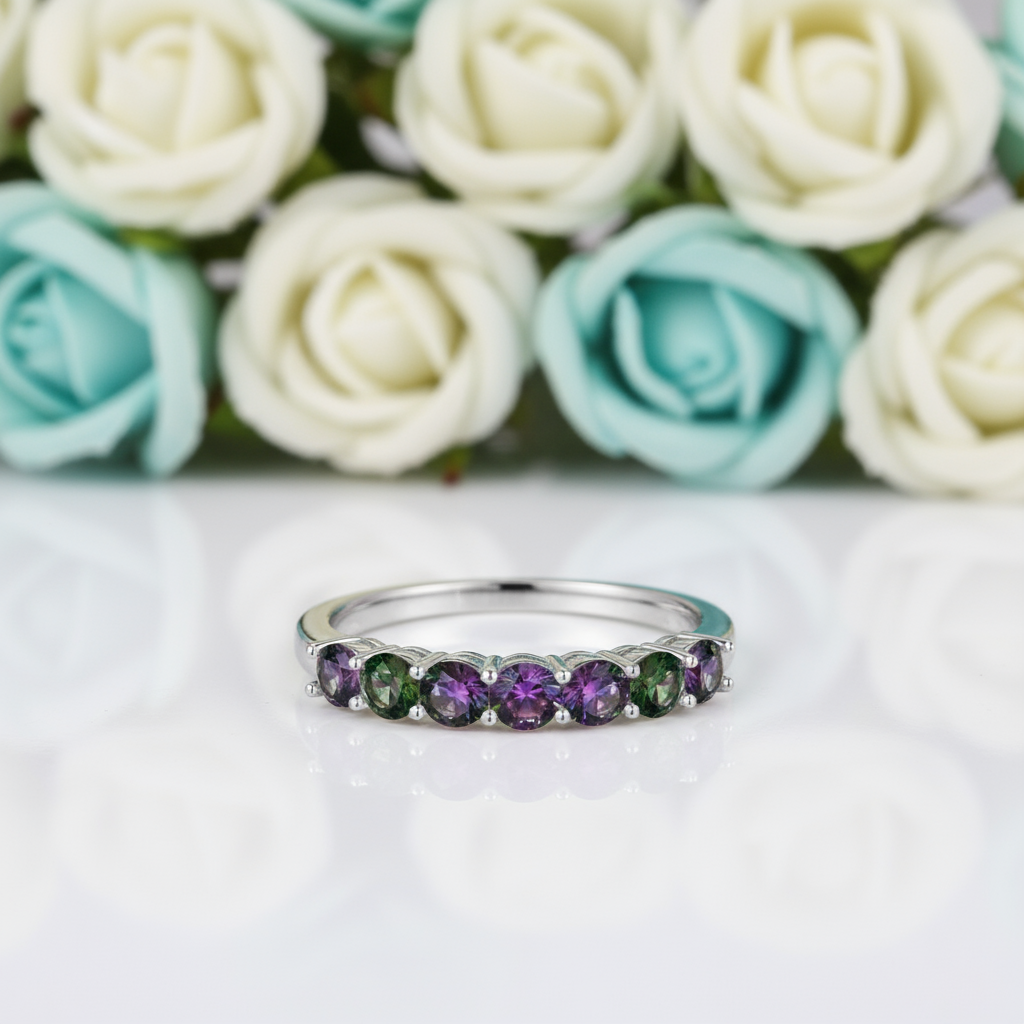 Silver ring with green and purple gemstones on a white background
