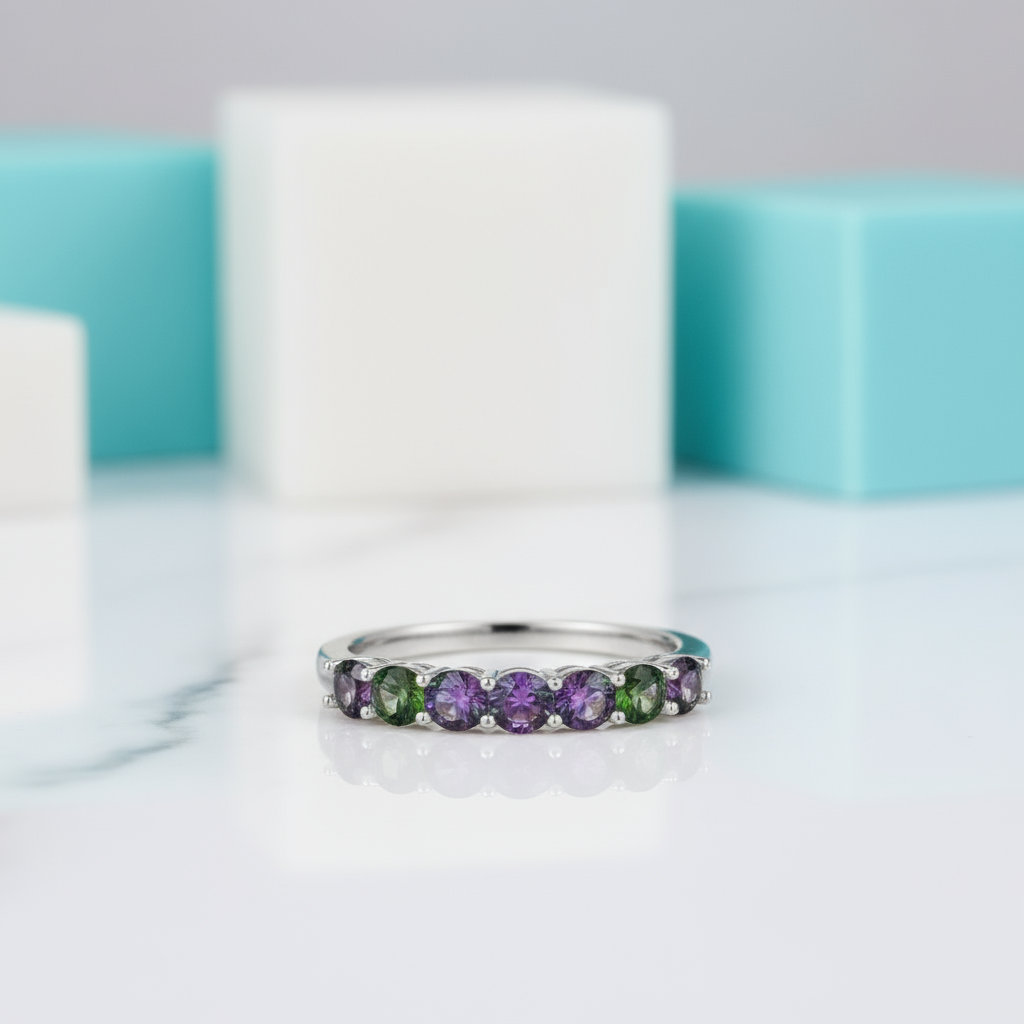 Silver ring with green and purple gemstones on a white background