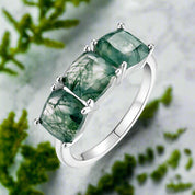 Silver ring with green gemstones on a white background