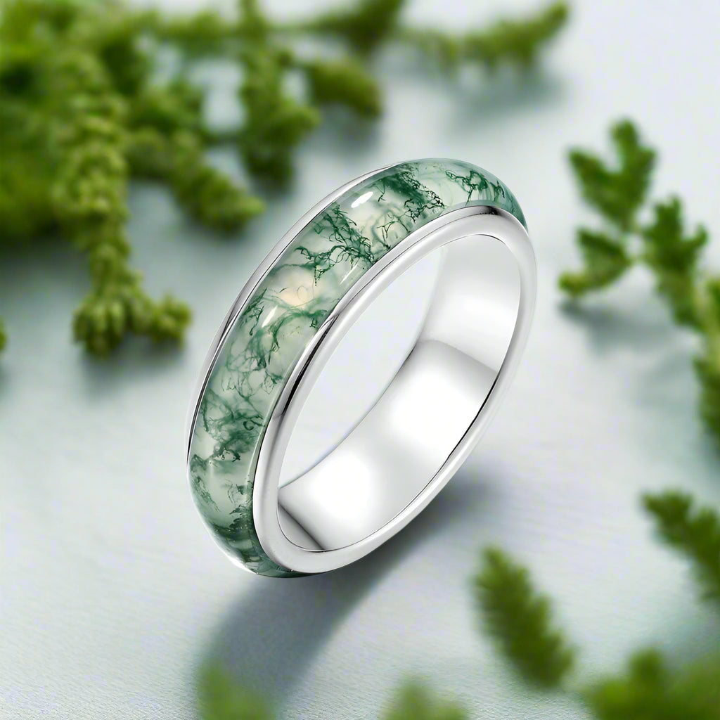 Silver ring with green marbled inlay on a white background