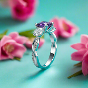 Silver ring with purple gemstone on a turquoise background