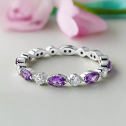 Silver ring with purple gemstones on a light background
