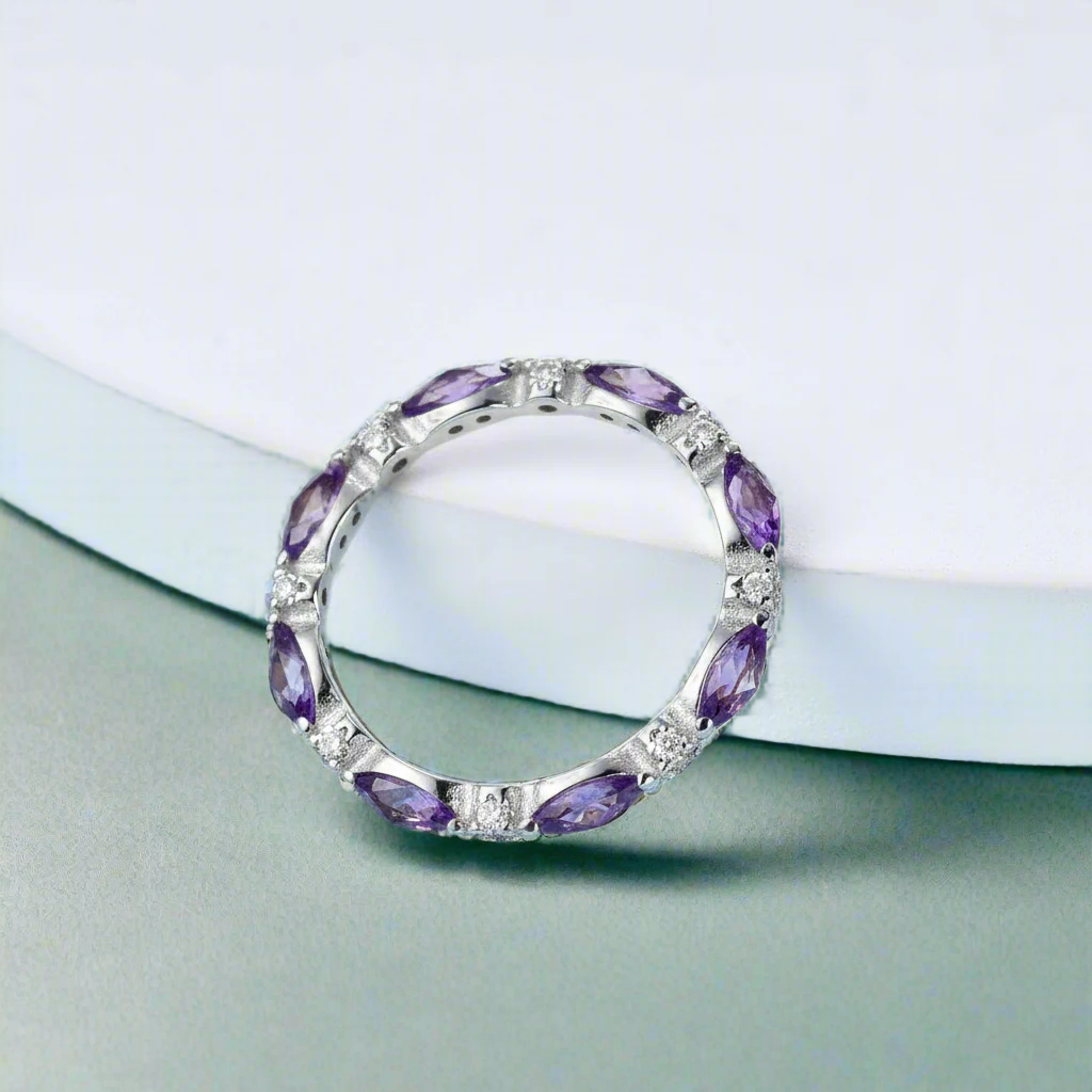 Silver ring with purple gemstones on a light blue background