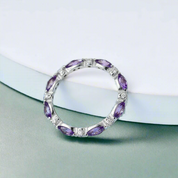 Silver ring with purple gemstones on a light blue background