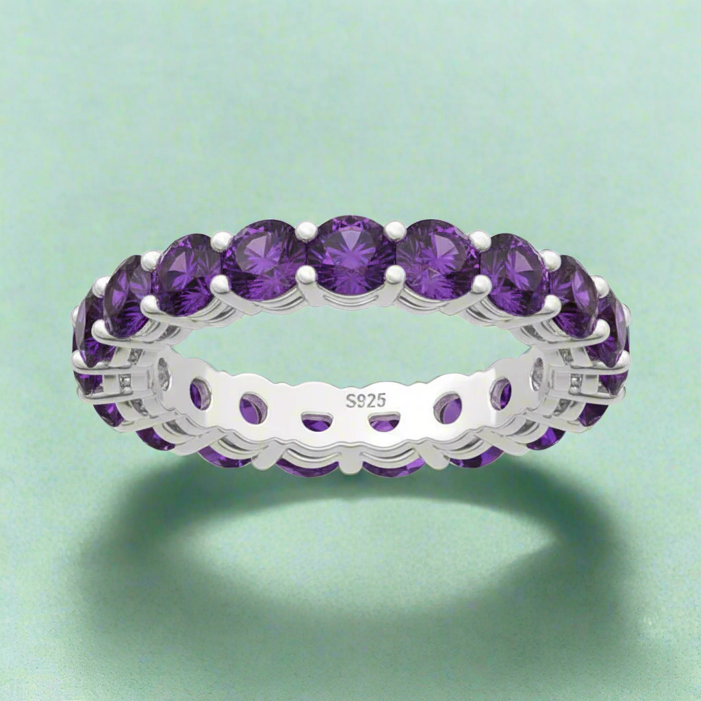 Silver ring with purple gemstones on a white background