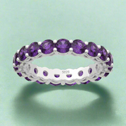 Silver ring with purple gemstones on a white background