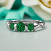 Silver ring with three green gemstones on a light background