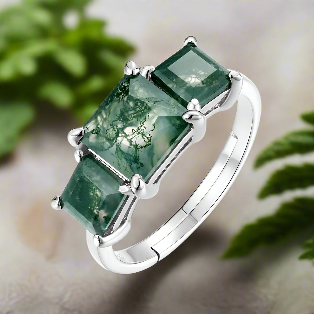 Silver ring with three green gemstones on a white background