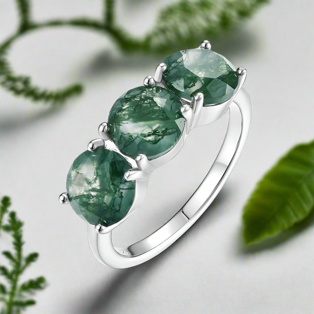 Silver ring with three green gemstones on a white background