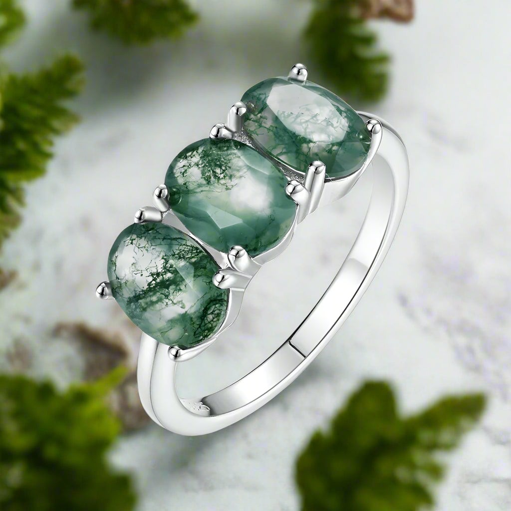Silver ring with three green gemstones on a white background