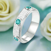 Silver ring with turquoise gemstones on a light background with white roses