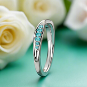 Silver ring with turquoise stones on a green surface with white roses