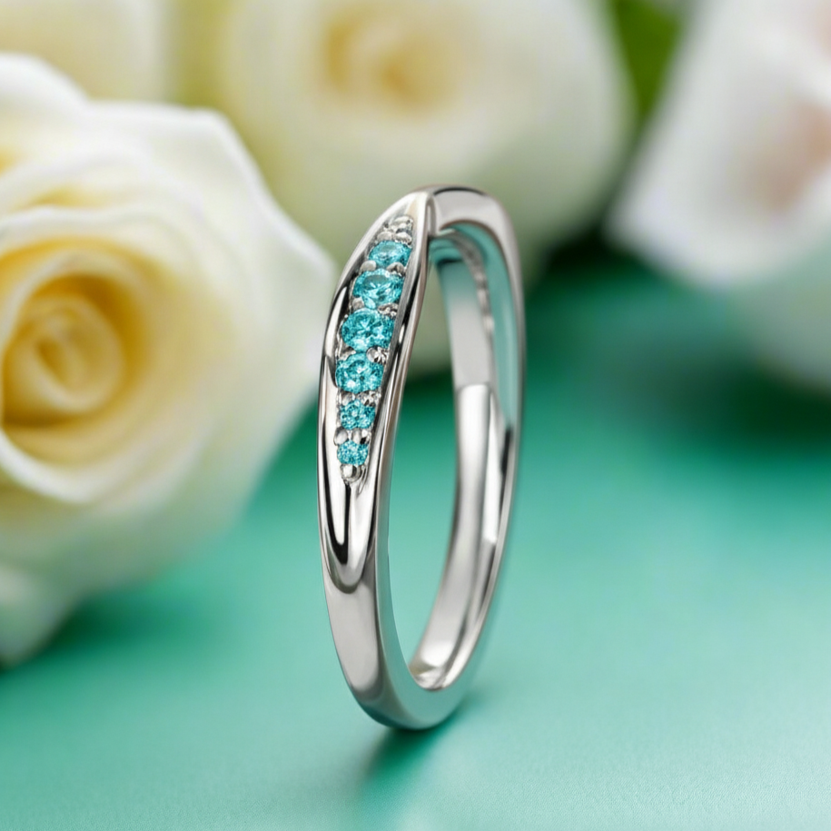Silver ring with turquoise stones on a green surface with white roses