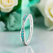 Silver ring with turquoise stones on a light green surface with flowers in the background