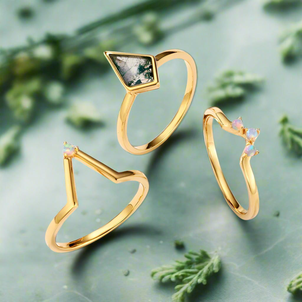 Three gold rings with gemstones on a light blue background