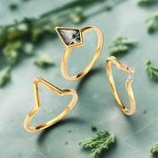 Three gold rings with gemstones on a light blue background