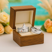 Three silver rings in a wooden box with flowers in the background