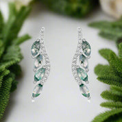 Pair of silver earrings with green gemstones on a white background