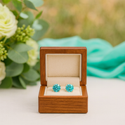 Turquoise earrings in a wooden box with flowers in the background