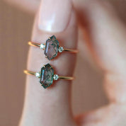 Two green gemstone rings on a finger with a blurred background