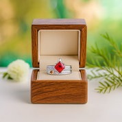 Two rings in a wooden box with a red gemstone on a natural background