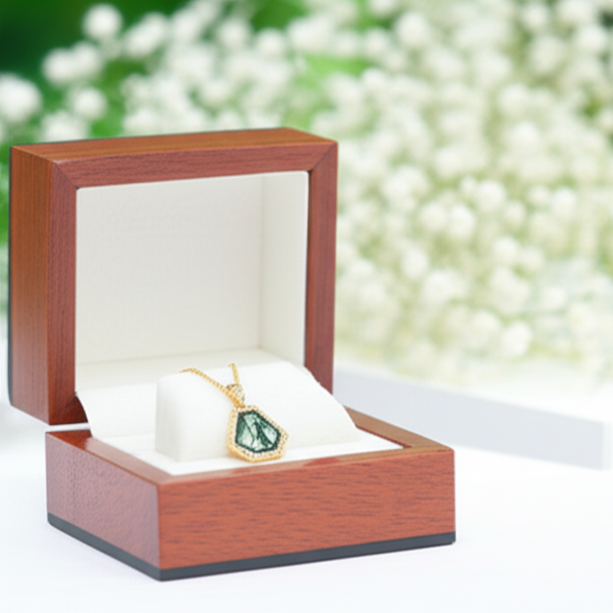 Wooden jewelry box with a green gemstone pendant on a blurred natural background