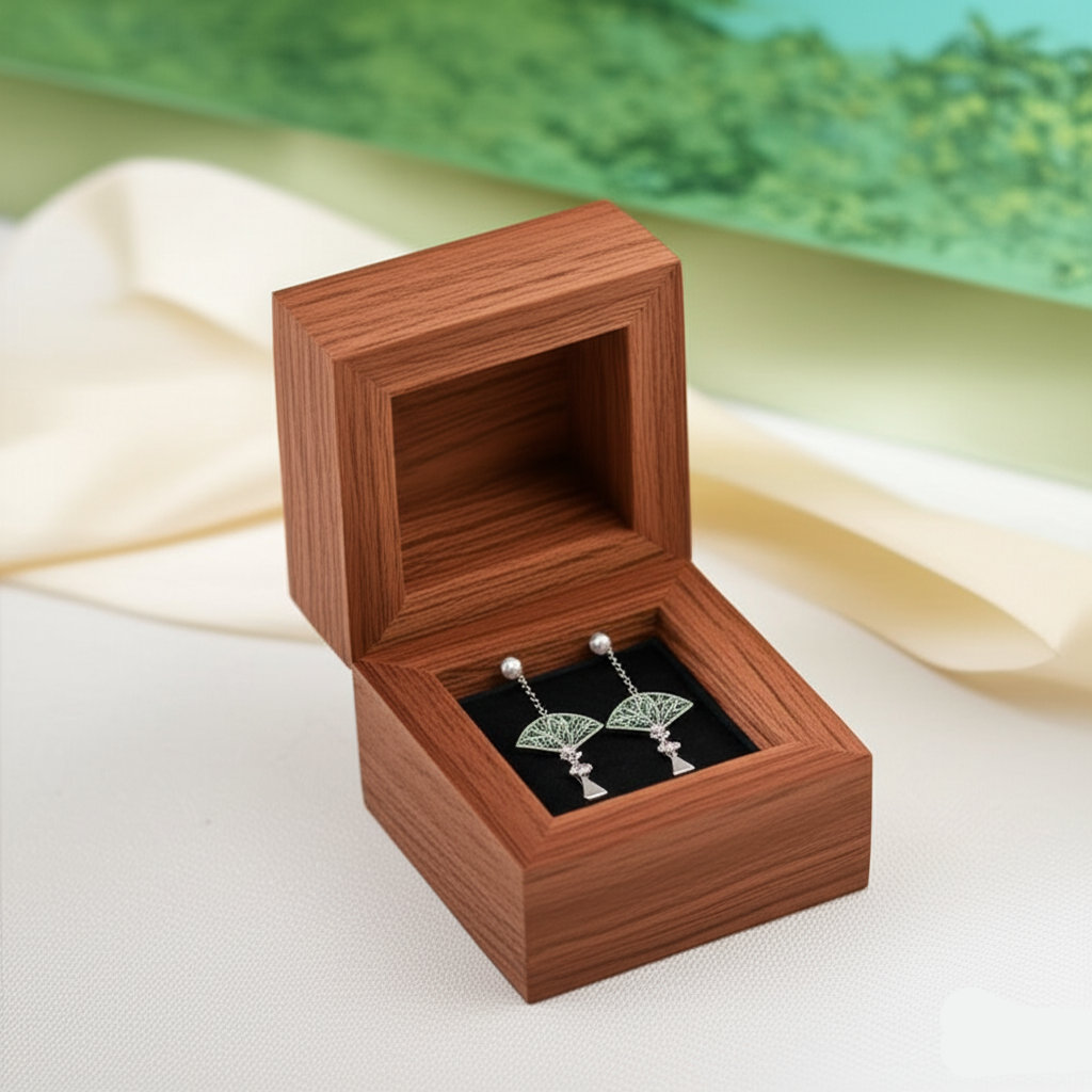 Wooden jewelry box with a pair of earrings on a light fabric background