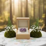 Wooden jewelry box with a purple brooch on a marble table in a forest setting