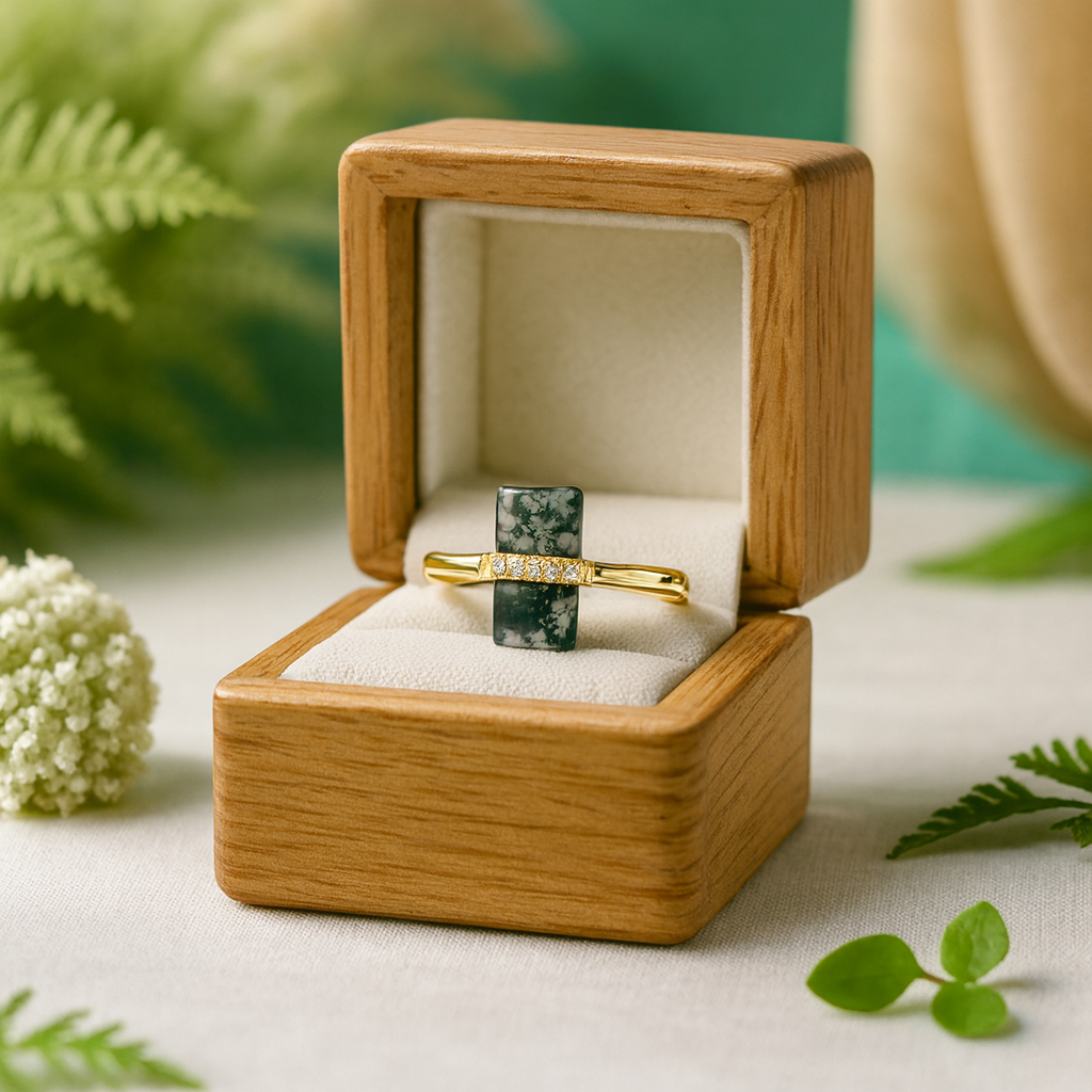 Wooden ring box with a gold ring and green stone on a natural background