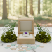 Wooden ring box with a purple gemstone on a marble surface with a forest background