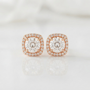 A pair of square cushion-cut halo stud earrings featuring large clear center stones surrounded by smaller round stones in a rose gold setting, displayed on a clean white reflective surface.