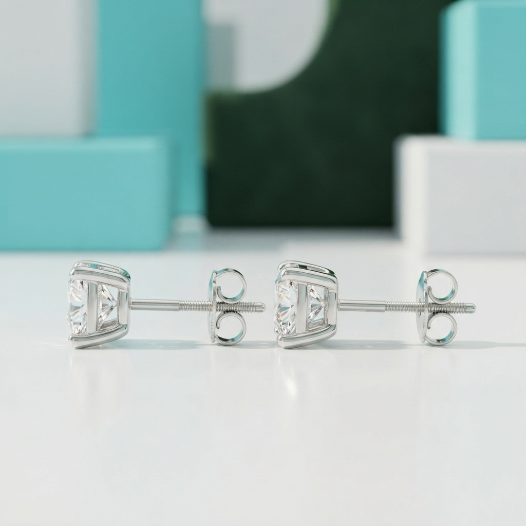 A pair of silver stud earrings with clear gemstones, displayed on a clean white surface with a soft-focus turquoise and green background.