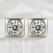 A pair of square stud earrings with large round-cut clear gemstones in a silver-toned bezel setting, shown on a clean white reflective surface.