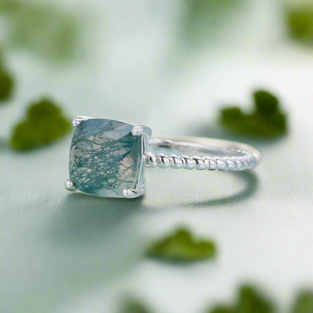 Silver ring with a green gemstone on a light blue background