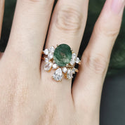 Ring with a green gemstone and diamond accents on a hand against a blurred background